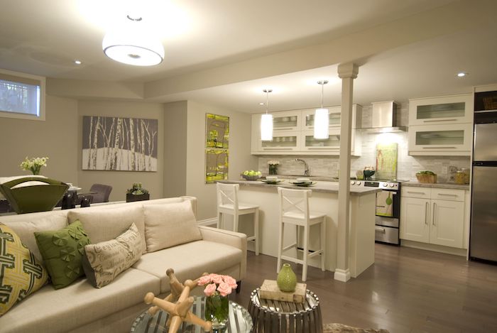 Offene Küche mit Wohnzimmer mit weißem Sofa und bunte Kissen, zwei weiße Stühle