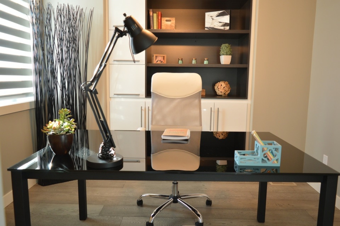 Arbeitszimmer in Creme, schwarzer Schreibtisch, blauer Stifthalter, kleine Grünpflanze, weißer Schrank mit schwarzen Regalen