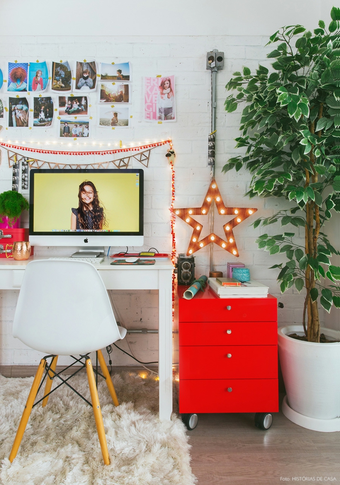 buntes Arbeitszimmer, weißer Schreibtisch und grellrote Schublade, große Grünpflanze, Fotos an der Wand, leuchtender Stern