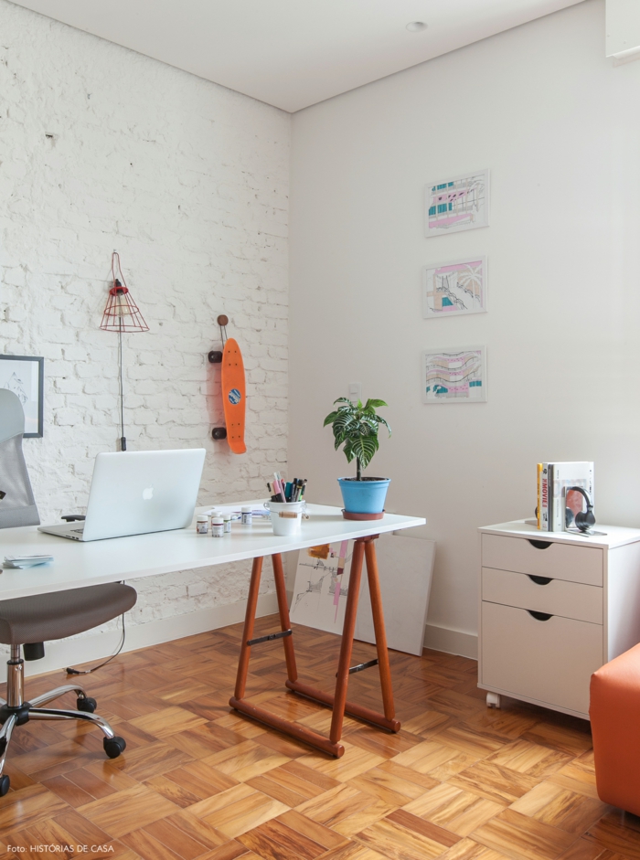 Arbeitszimmer in Weiß, Schreibzisch aus Holz, grauer Lederstuhl mit Rollen, Skateboard an der Wand