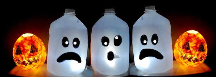 einfach Halloween Deko basteln - drei Flaschen mit Lampen und zwei Vasen wie Jack O'Lantern 