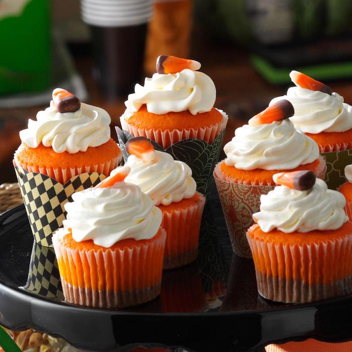 halloween gebäck, cupcakes in orange und braun dekoriert mit sahne und geleebonbons