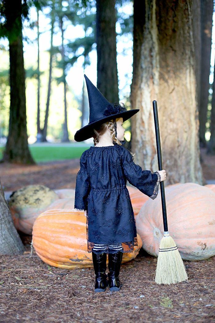 eine kleine, süße Hexe, Halloween Kostüm für Mädchen, riesige Kürbisse, Herbst im Wald