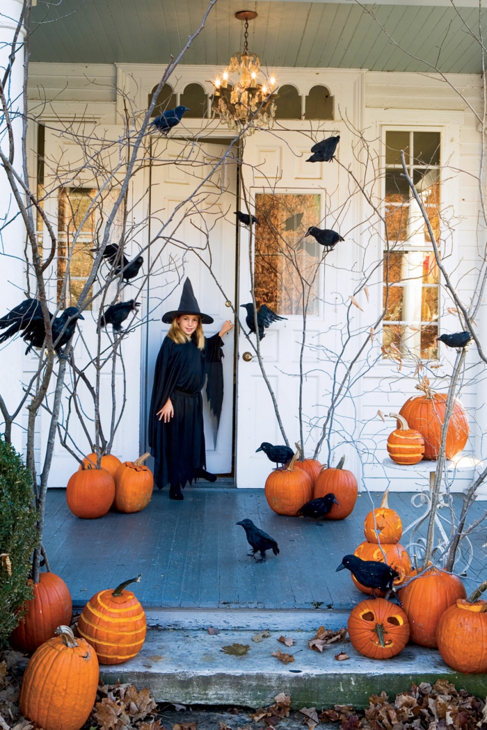 Halloween Dekoration, viele Kürbisse und Raben, eine kleine Hexe vor der Tür, Kürbisse schnitzen
