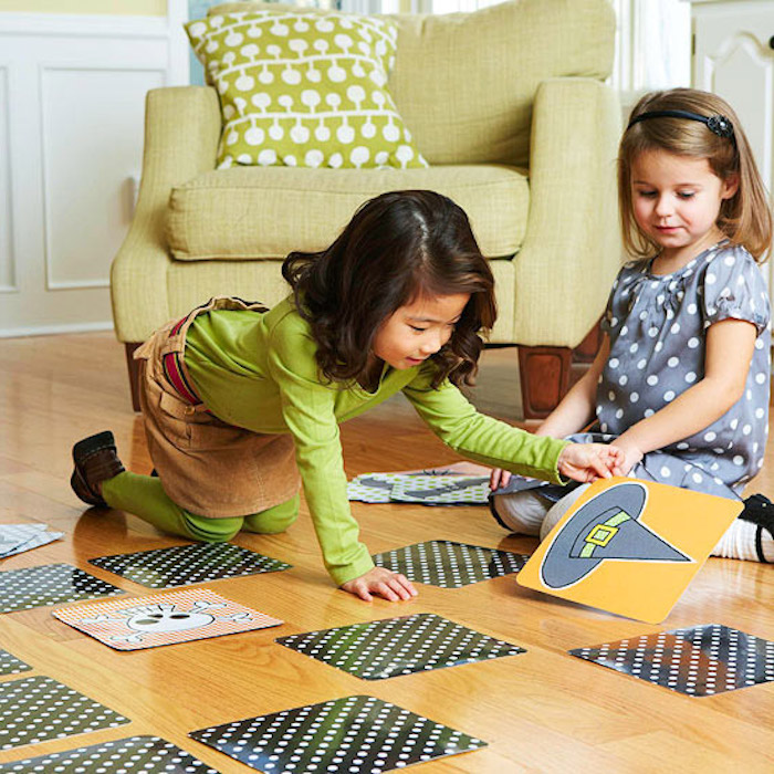 Halloween Spiele, zwei kleine Mädchen spielen mit Karten auf dem Boden im Wohnzimmer