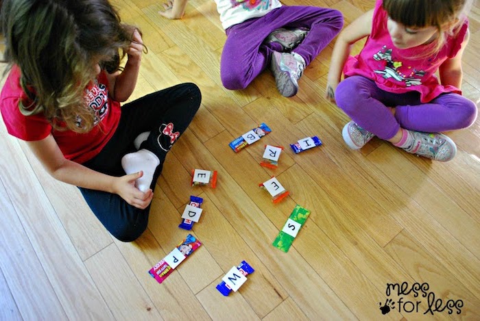 Kinder in Sportkleidung spielen Scrabble mit Kaugummis auf dem Boden