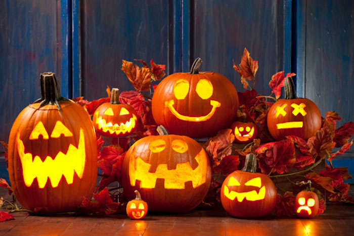 tolle Halloween Deko mit Kerzen und Kürbissen, buntes Laub, dunkelblaue Holzwand