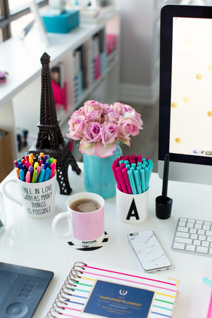 weißer Schreibtisch, Rosenstrauss in blauem Einmachglas, Tassen als Stifthalter, buntes Heft, Tasse Tee, PC und Handy
