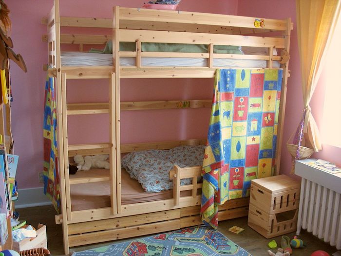 Kinderbett mit bunten Vorhängen interessant bemustert, bunter Teppich und Bettwäsche