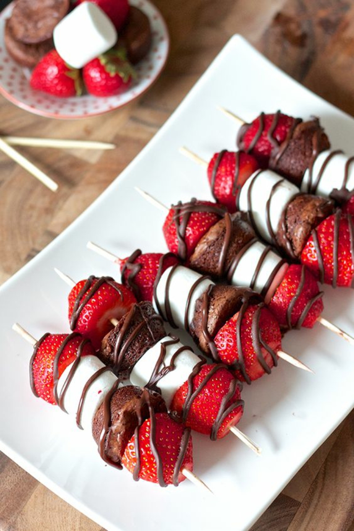 Süße Partyhäppchen, Erdbeeren, Marshmallows und kleine Kekse mit Schokolade verzieren