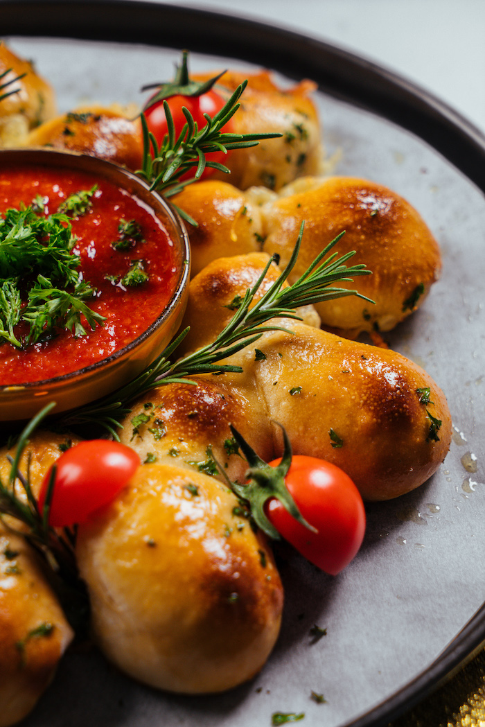 Frischgebackenes Brot mit Babymozzarella, mit Tomatendip und frischem Rosmarin servieren 