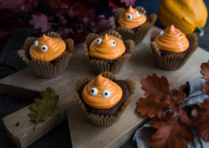 halloween backen, cupcakes dekoriert mit oranger sahne und augen aus schokolade