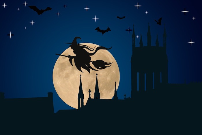 Halloween Hintergrund - eine Hexe am Besen fliegt über einer mittelalterlichen Stadt