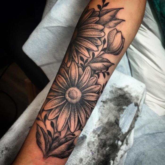 tattoo bedeutung, frau mit großer schwarz-grauer tätowierung mit gänseblume-motiv