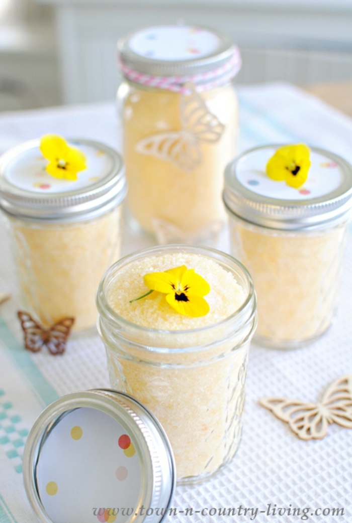 Badesalz mit Zitrone in Einmachgläsern, gelbe Stiefmütterchen darauf, verziert mit Schmetterlingen aus Holz