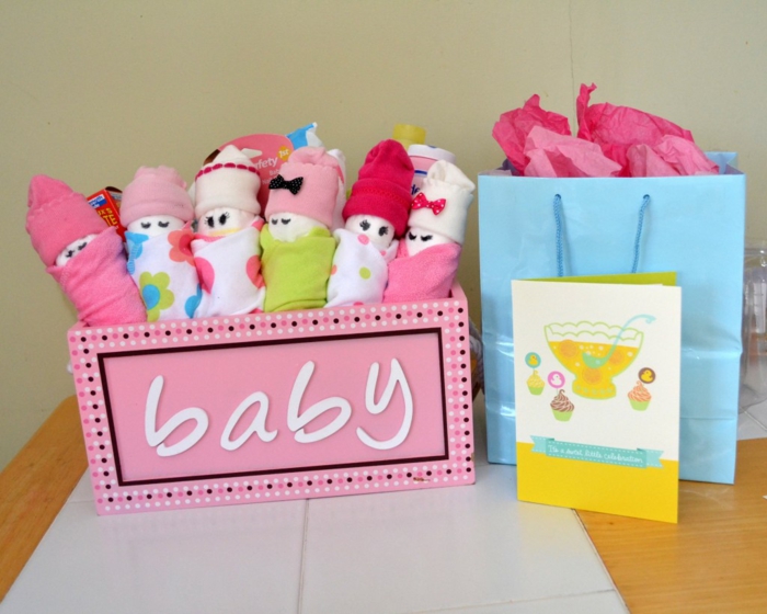 Bunte Tücher und Babysöckchen in Form von Babys, eine Grußkarte mit Cupcakes und Punsch, blaue Verpackung