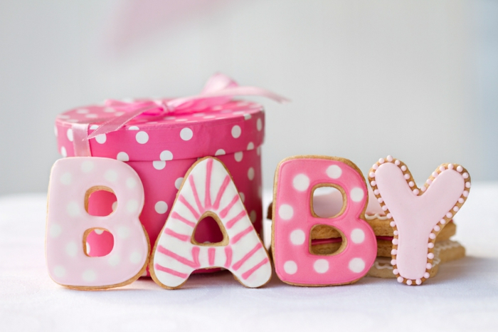 Schöne Geschenkideen zur Geburt, Kekse als Buchstaben, rosafarbene Verpackung mit weißen Punkten und Band
