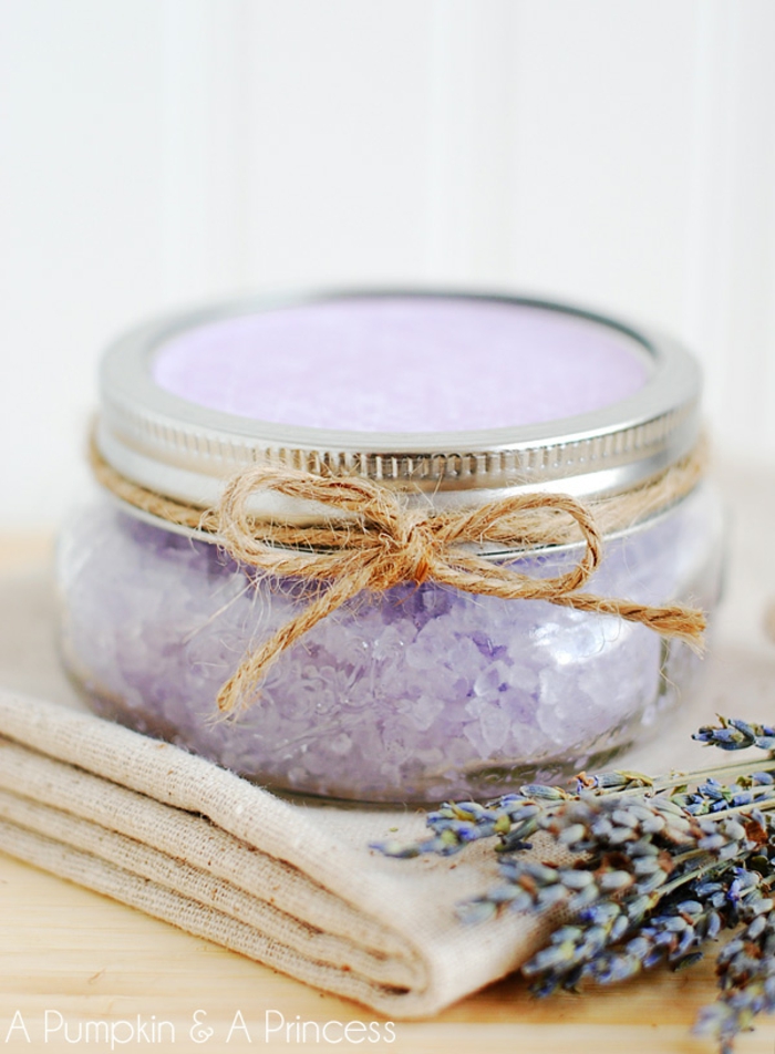 Badesalz mit Lavendel in kleinem Einmachglas, mit Faden verziert, Lavendelblüten daneben