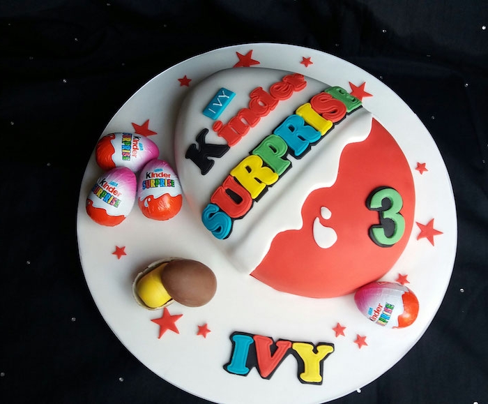Kinderriegel Torte in vielen Farben, mit kleinen Überraschungseier darum und der Name der Dreijährige