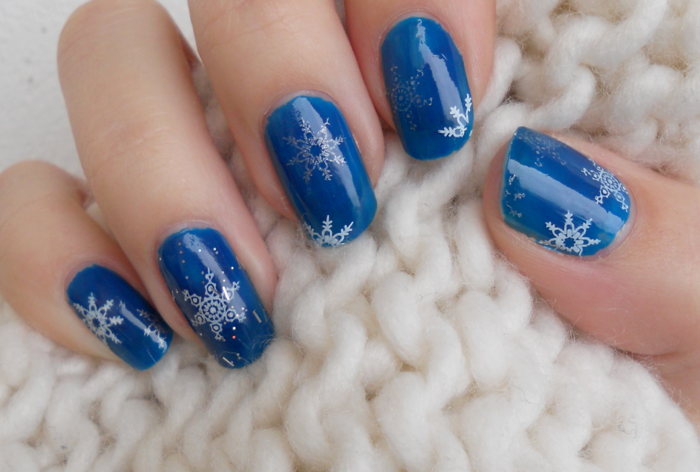 Weiße und silberne Schneeflocken auf dunkelblauem Grund, runde Nagelform, Winter Nageldesign zum Nachstylen