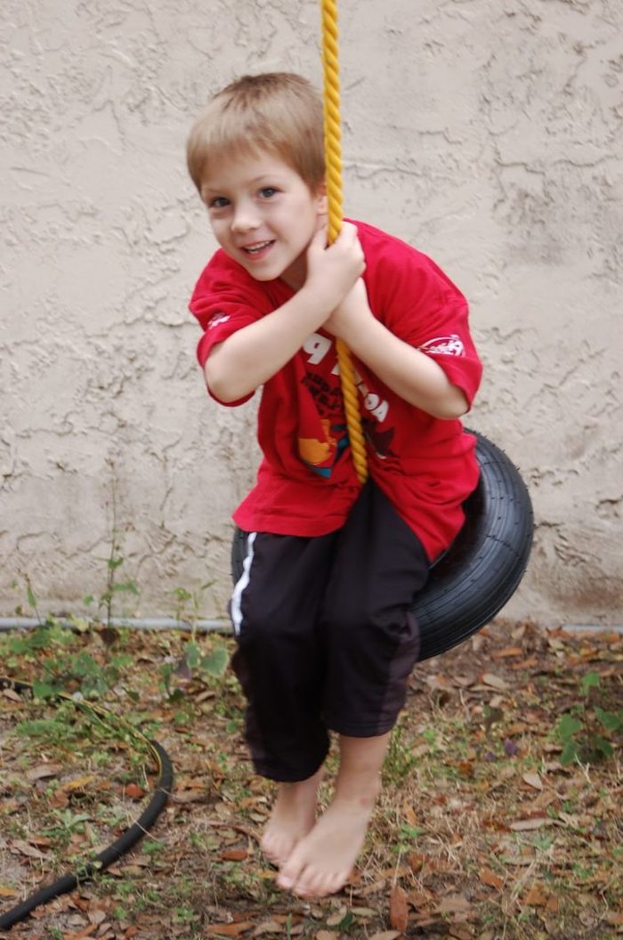 eine einfache Schaukel bauen aus Reifen und Seil, Junge mit einem Traininganzug