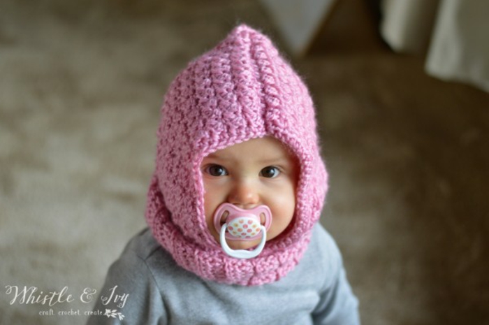 Selbstgestrickte rosafarbene Kapuze, schönes Geschenk zur Geburt selber machen, süßes Baby mit großen schwarzen Augen