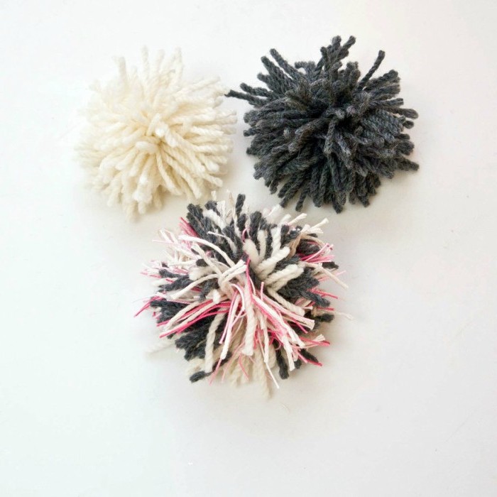 drei Pompoms in schwarzer, weißer und rosa Farbe - schnell und einfach Katzenspielzeuge basteln