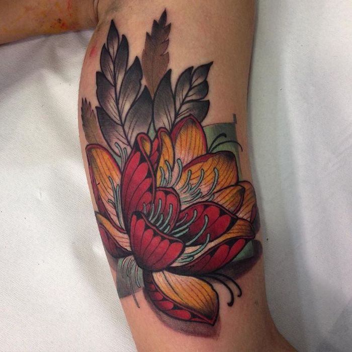 tattoo blume, lotusblume in rot und orange am oberarm, arm tätowieren