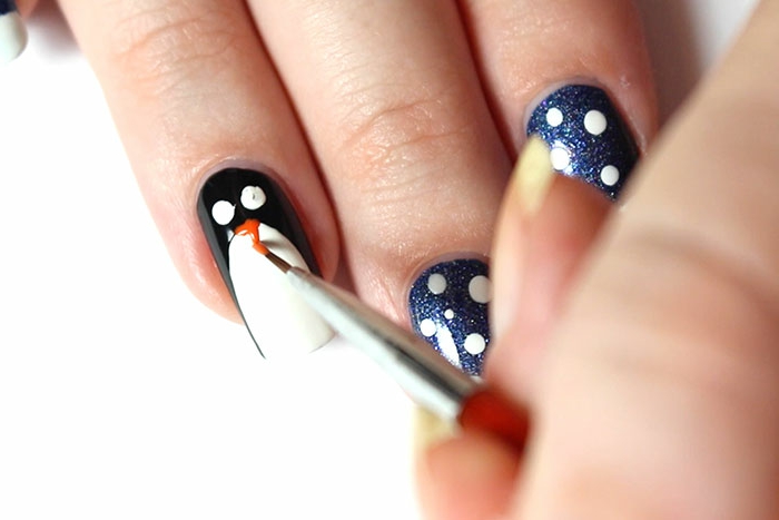 Idee für Wintermaniküre, Pinguin und kleine Schneeflocken aufzeichnen, dunkler Grund, ovale Nagelform
