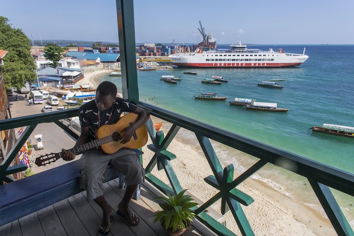 sansibar stadt schönes ambiente in tansania mann einheimischer spielt gitarre auf der terrasse wasser schiff aussicht oben über das wasser