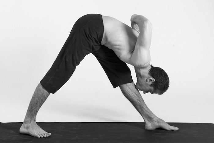 ein Mann macht Yoga, das Bein mit dem Kinn berühren, sich nach vorne lehnen, schwarz-weißes-Foto