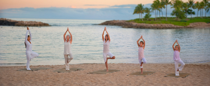 drei Frauen und zwei Kinder machen Yoga am Strand, zwei kleine Insel mit Palmen, Sonnenuntergang