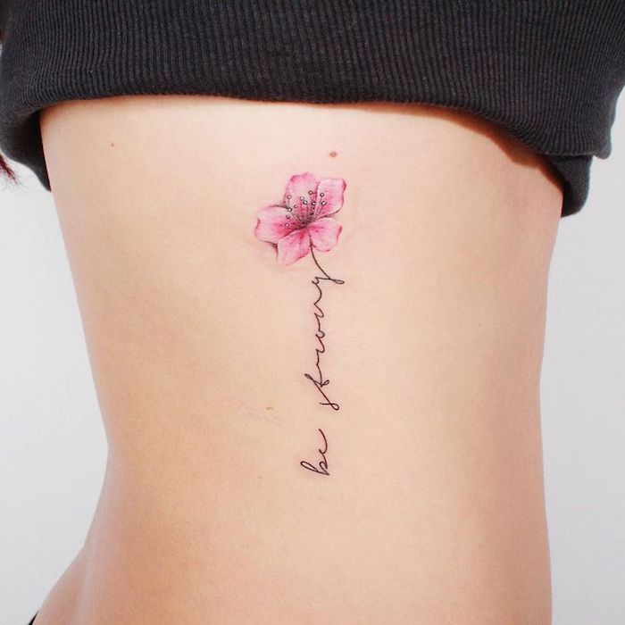 tattoo schriftzug, frau mi klener tätowierung mi blumen motiv an der körperseite