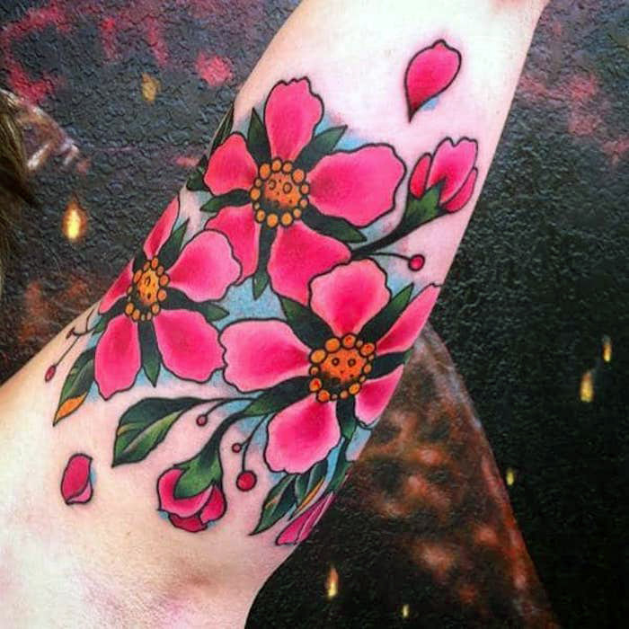 blumenranke tattoo am oberarm, tätowierung mit rosa kirschblüten als motiv