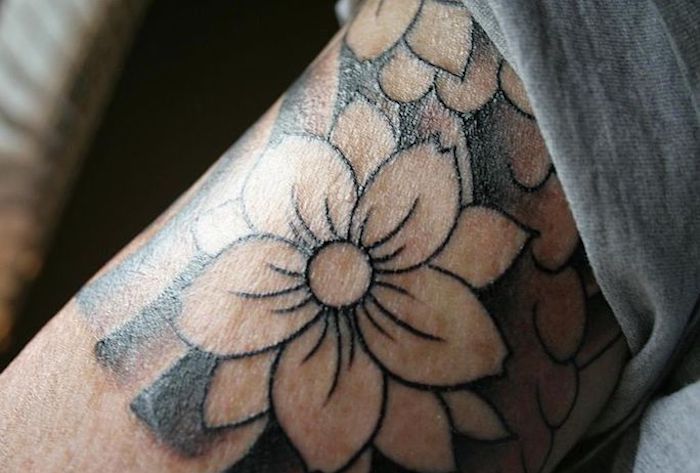 tattoo beudetung, tätowierung mit blumen-motiv in schwarz und grau