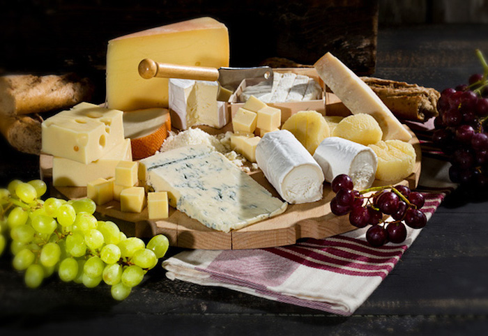 Käse mit Weißmehl- und Vollkorn-Baguett, Emmentalerkäse mit Löchern, Camember mit einer eingeschlagenen Hackmesser, rot-weißer Handtuch mit Streifenmuster