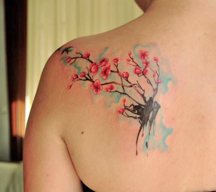 tattoos mit bedeutung, frau mit wasserfarben tattoo am rücken