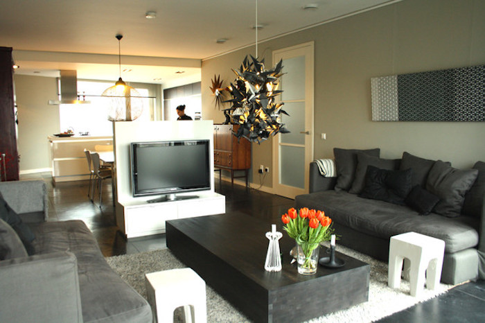 tv wand kreatives design in der mitte des zimmers wohndesign tisch zwei sofas und frische tulpen auf dem tisch küche auf der anderen seite