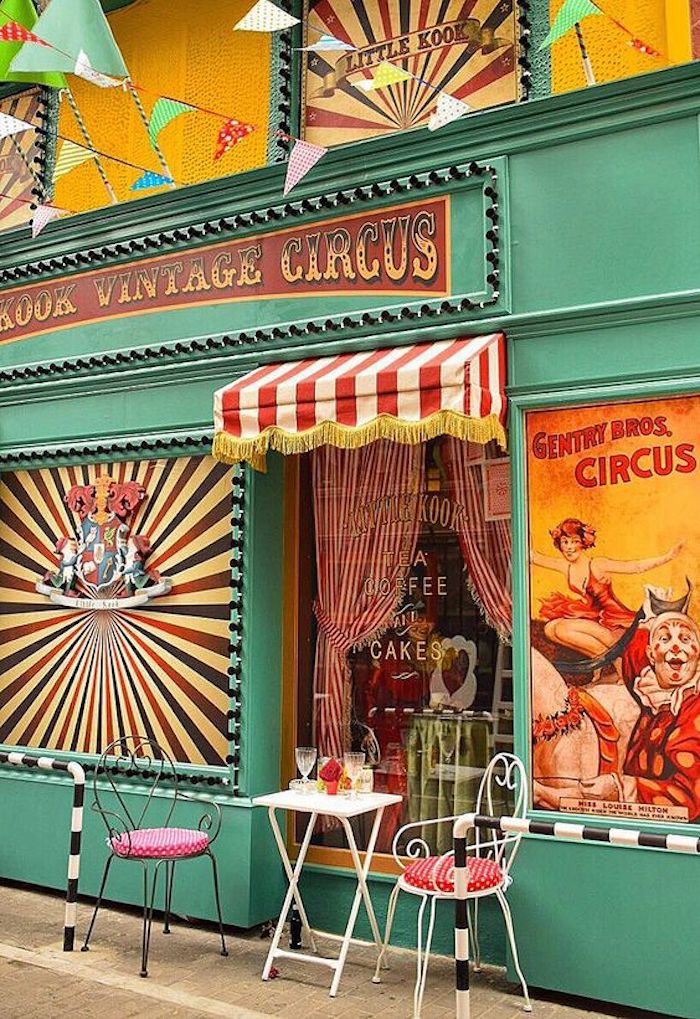 athen sehenswürdigkeiten ein faszinierendes geschäft mintgrün fassade zirkus shop mintgrüne farbe gemälde zirkusspieler clown lutscher motive deko bunte farben rosarote stühle sitzkissen