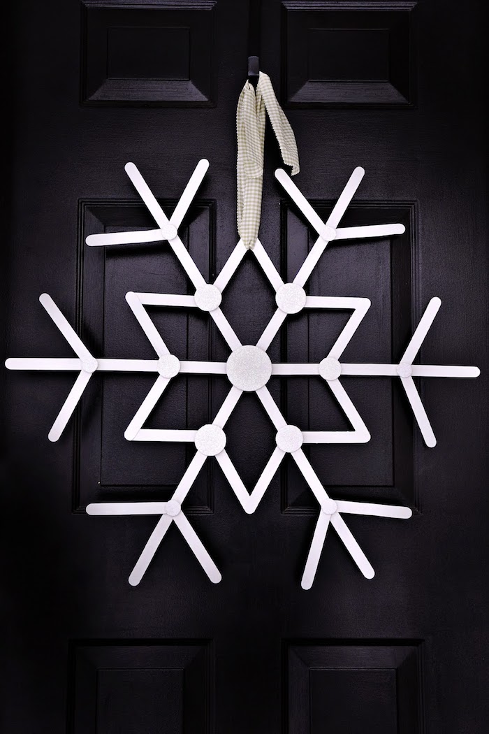 weiße Schneeflocke an einer dunklen Tür mit einem weißen Band gebunden - Schneeflocken basteln