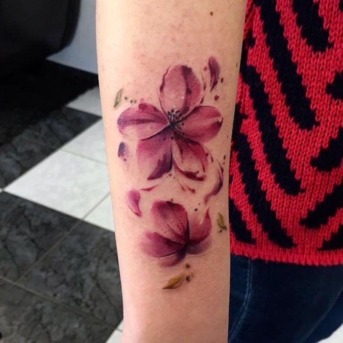blumenranke tattoo am unterarm, rosa blüten mit wegfliegenden blüttenblättern