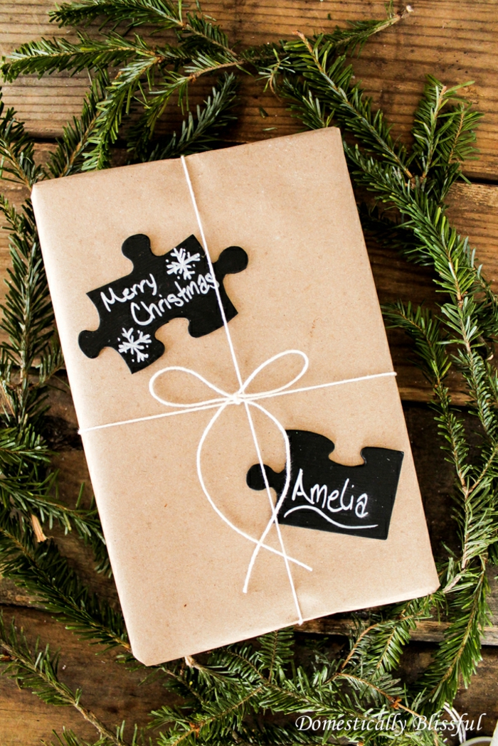 Geschenkverpackung mit Puzzlestücken verziert, kreative Geschenkideen zu Weihnachten, frische Tannenzweige