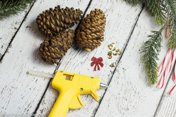 Zapfen selber verzieren, Pailletten mithilfe einer Heißklebepistole befestigen, DIY Ideen für Weihnachtsschmuck