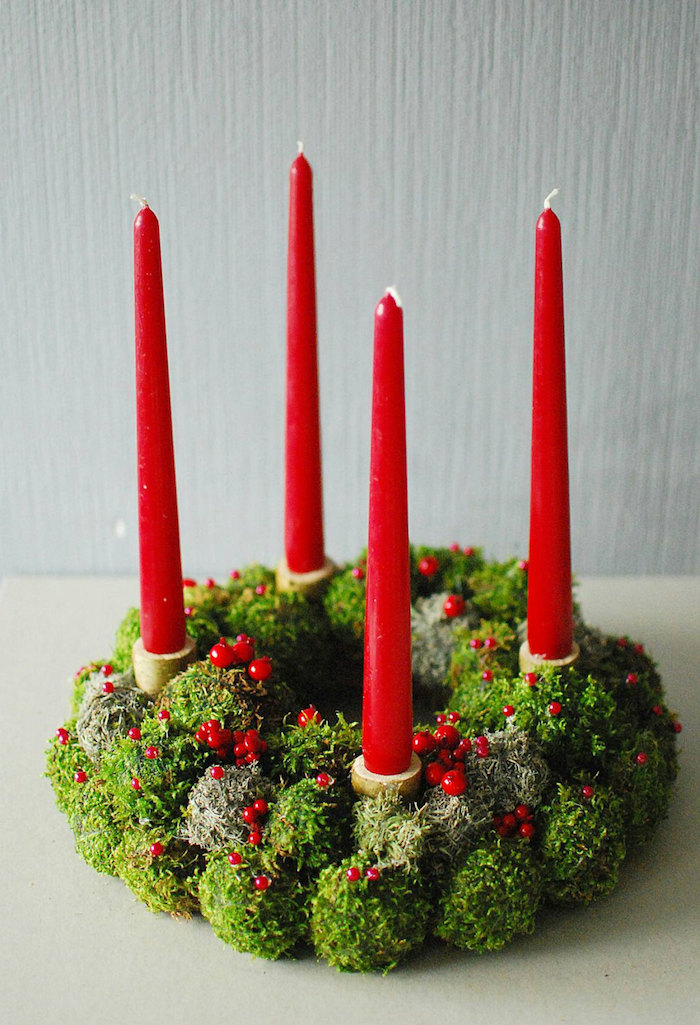 ein großer adventskranz mit kleinen roten früchten und vier langen großen roten kerzen und grünen pflanzen - einen adventskranz selber binden