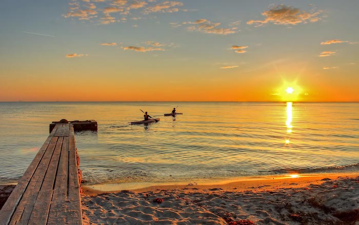 zwei Boote segeln im Meer beim Sonnenaufgang, das Wasser scheint rot zu sein - Guten Morgen Bilder
