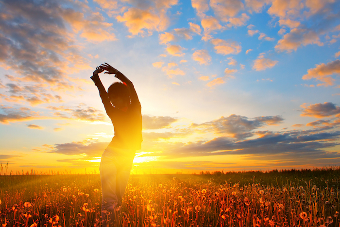 ein Mensch turnt am Tagesanbruch auf einer Wiese mit Pusteblumen - Guten Morgen Bilder
