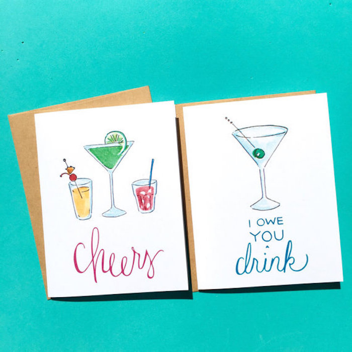 zwei Schuldscheine für Cocktail-Aben, weiße Karte mit drei Alkoholgetränken und mit Cheers-Anschrift, eine IOY-Karte mit Martiniglas mit einer grünen Olive, zwei braune Umschläge für Postkarten, Bild mit türkisblauer Hintergrund 