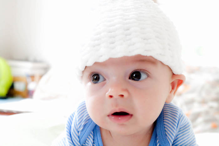 ein kleines Baby mit großen braunen Augen und süße weiße gestrickte Mütze - einen wunderschönen Guten Morgen