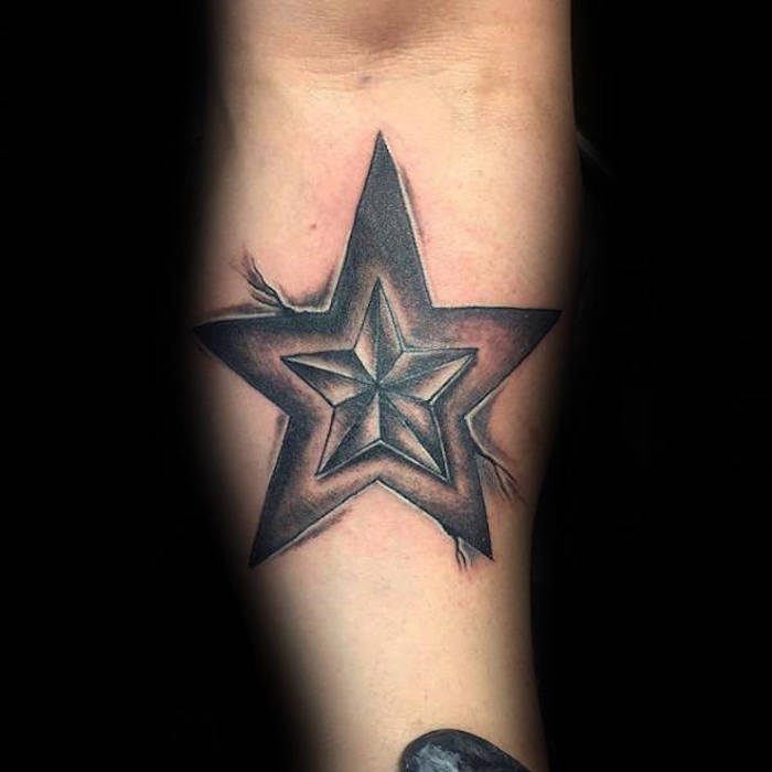 hand mit einem schwarzen tattoo mit einem kleinen stern und einem großen schwarzen stern