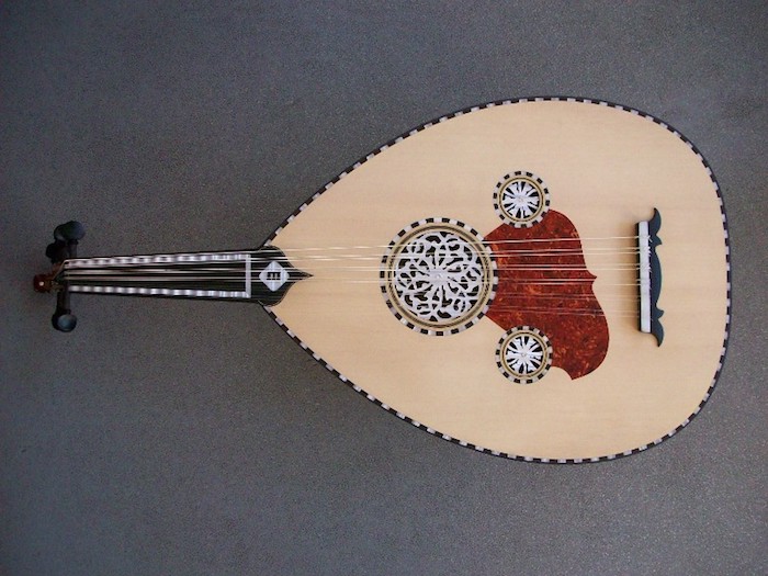 Oud mit kurzem Griff mit silbernen Kanten, ovaler Korpus aus hellem Holz, schöne Holzschnitzereien mit Mandala-Motiven, ein großer roter Fleck auf der Vorderseite des Instruments